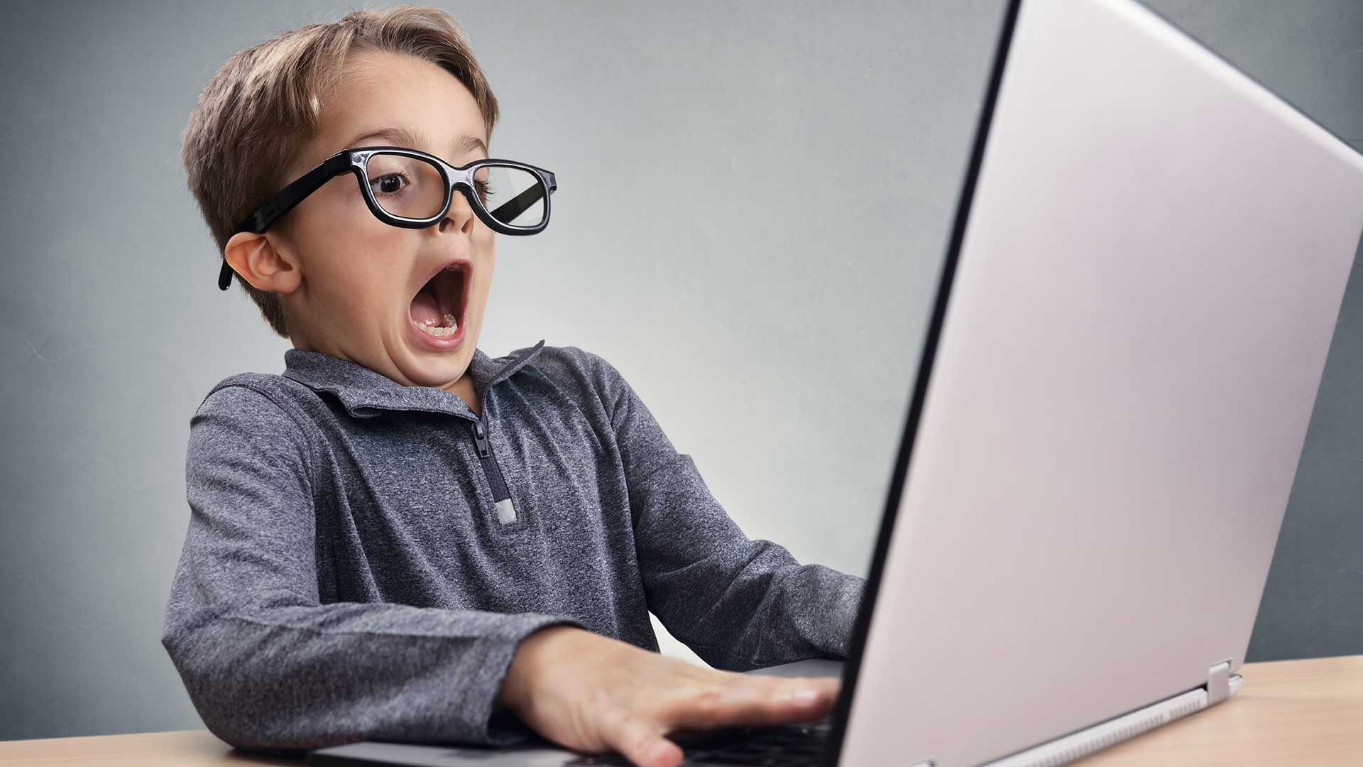 Foto: jongetje kijkt verschrikt naar een computerscherm