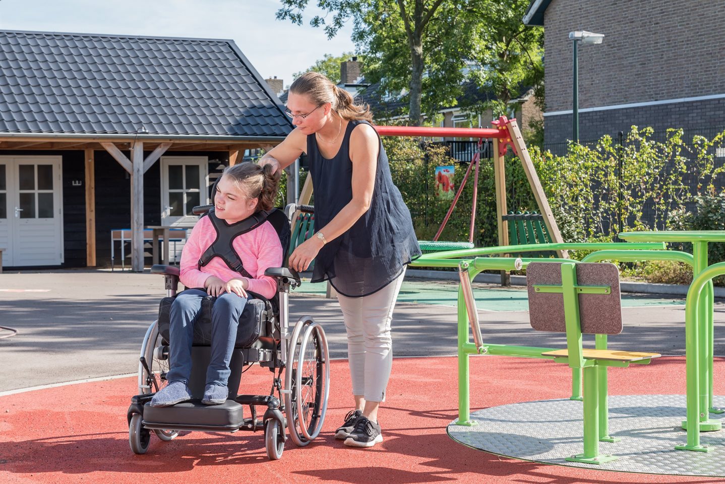 Foto: meisje in rolstoel wordt voortgeduwd door begeleidster